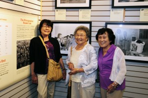 (From left) Anne Enoki, Rose Sorenson and Kay Yamaguchi stand in front of the image Russell Lee took of them in 1942, shown above. Photo by David Nishitani